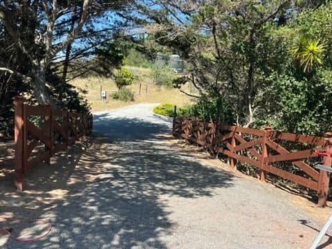 Wooded driveway with a crossbuck fence and open gate