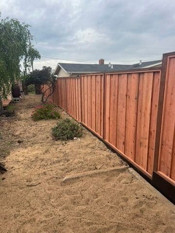 Long redwood privacy fence running along a backyard