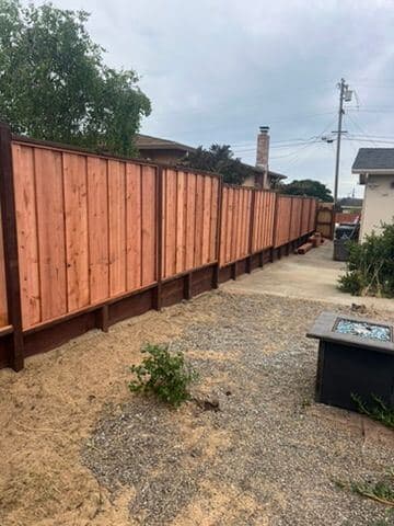 Wide view of a finished redwood privacy fence line and yard